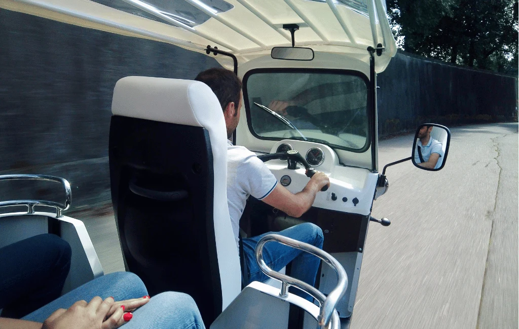 Motorista a conduzir um tuk tuk visto de trás